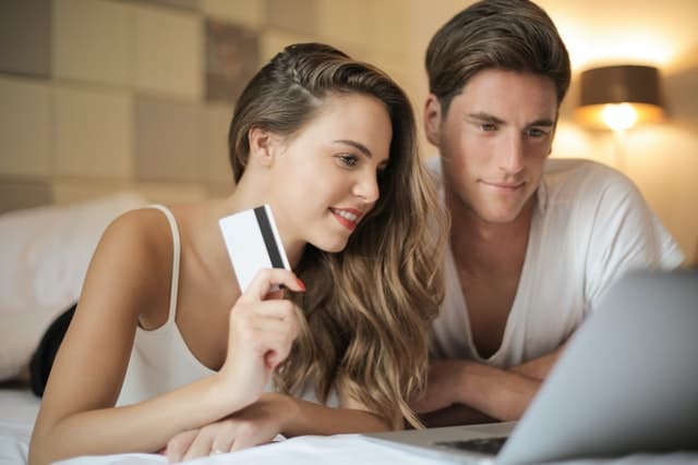A young couple enter credit card details to complete an ecommerce purchase on a laptop